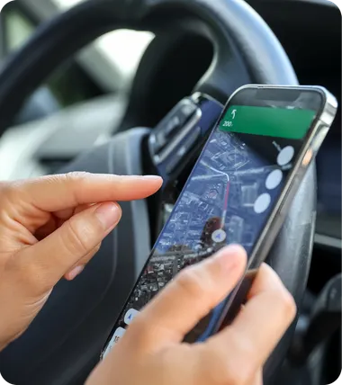 Hands holding a phone with a map open, in a car.
