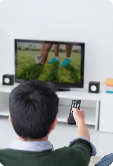 A man watches television from his sofa, remote in hand.