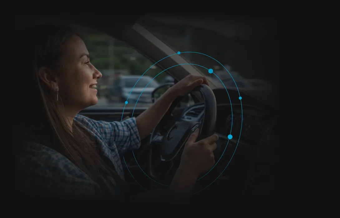 A woman smiling as she drives.