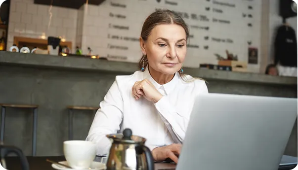 A woman in a cafe looking at her laptop.