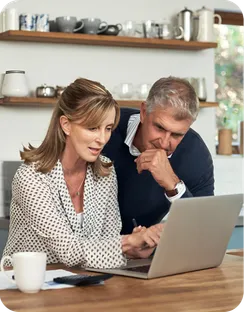 A couple look at a laptop together at home.
