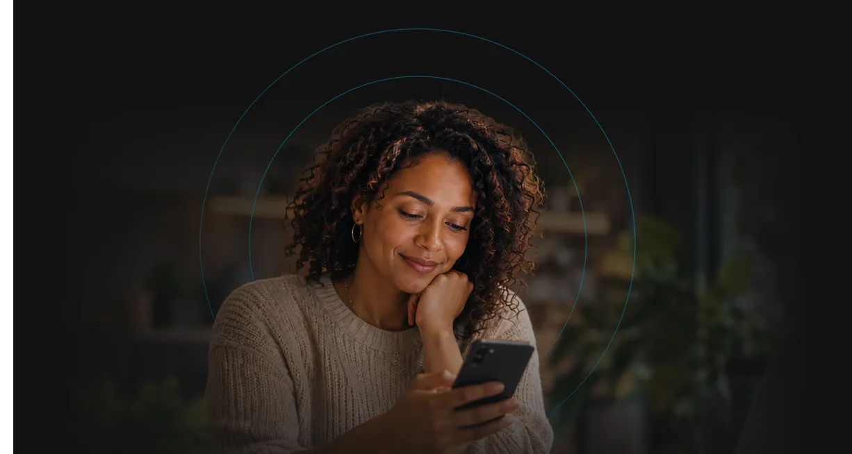 A woman smiling at her phone.