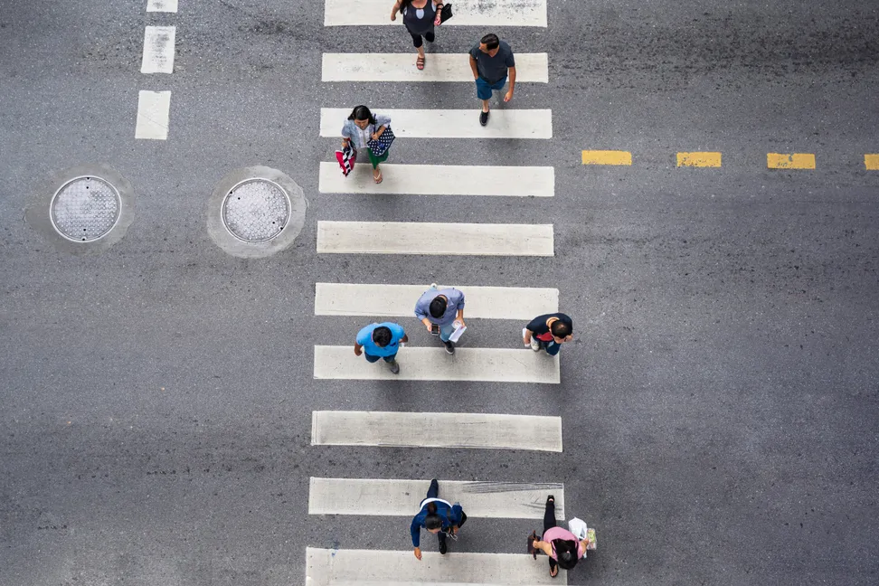 People crossing a city street, seen from above.