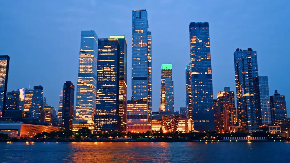 The Hudson Yards towers in New York at dusk, lit windows over the river.