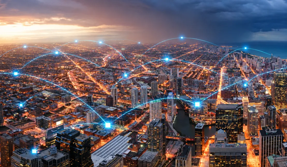 An aerial view of a city at night, with lines of light linking points across it.
