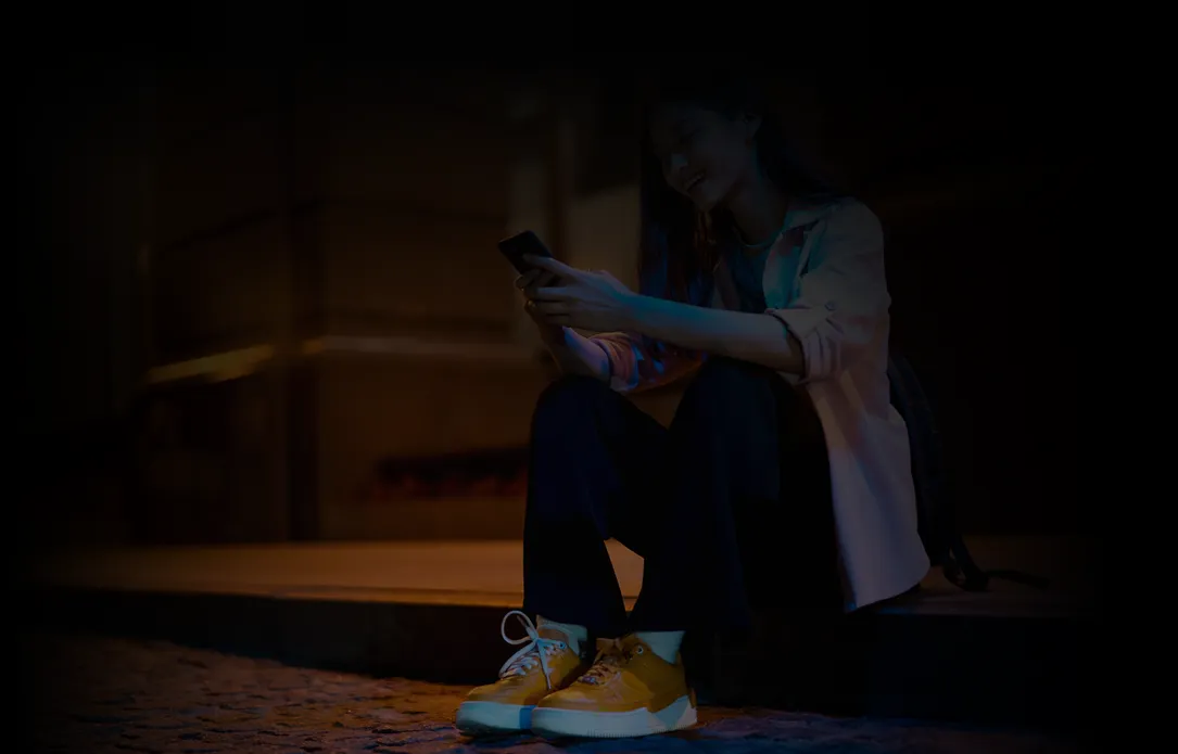 A woman smiling at her phone.