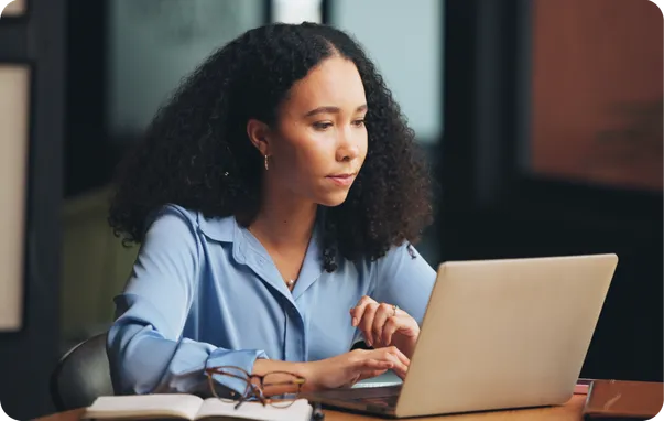 A woman working on a laptop at a desk.