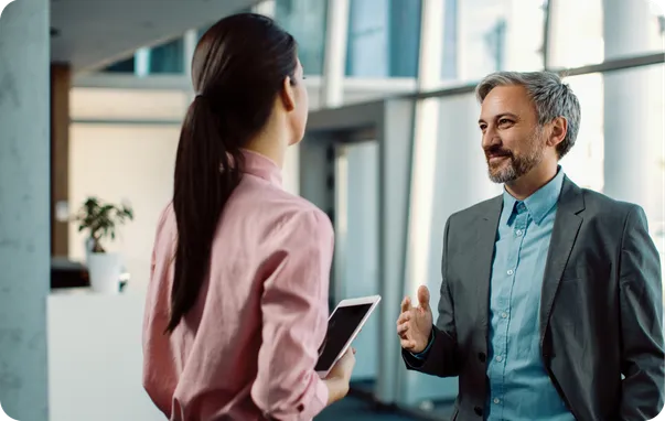 A woman and a man in suits talking in an office lobby.