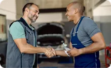 Two mechanics shaking hands in a repair shop.