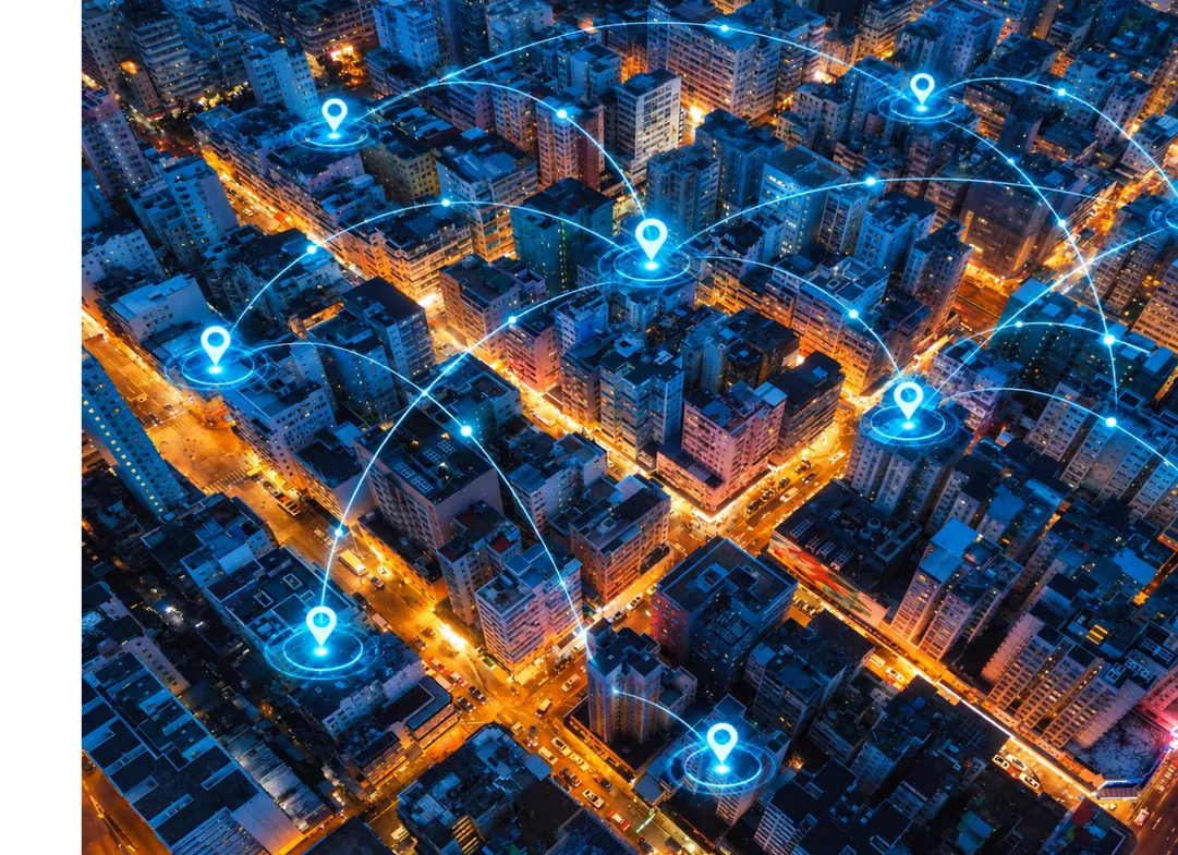 An aerial view of a city at night, with glowing map pins joined by arcs of light.