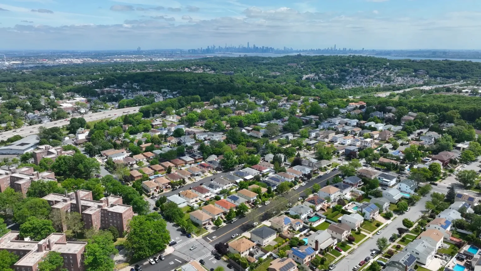 An aerial view of a suburban neighborhood with a city skyline on the horizon.