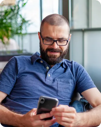A man relaxes on a sofa, looking at his phone.