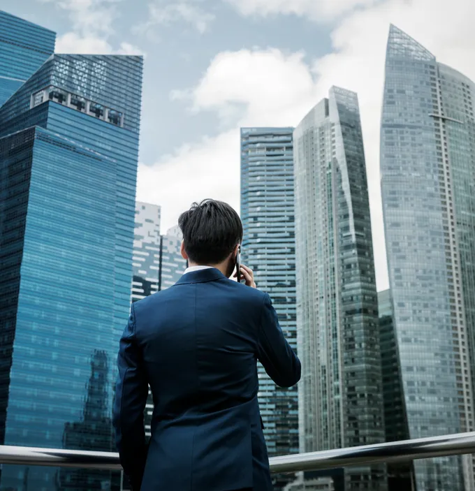 A man in a suit on a phone call among city towers.
