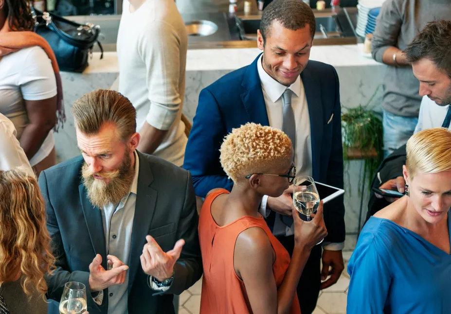 Business people talking over drinks at a crowded reception.