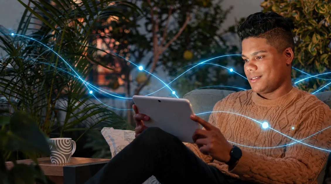 A young man smiling at a tablet.