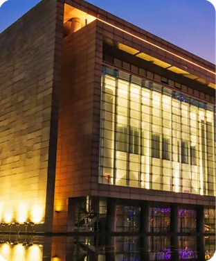 A dated brick and glass building lit at dusk.